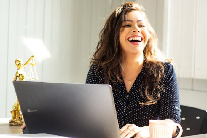 Woman laughing and working on her laptop